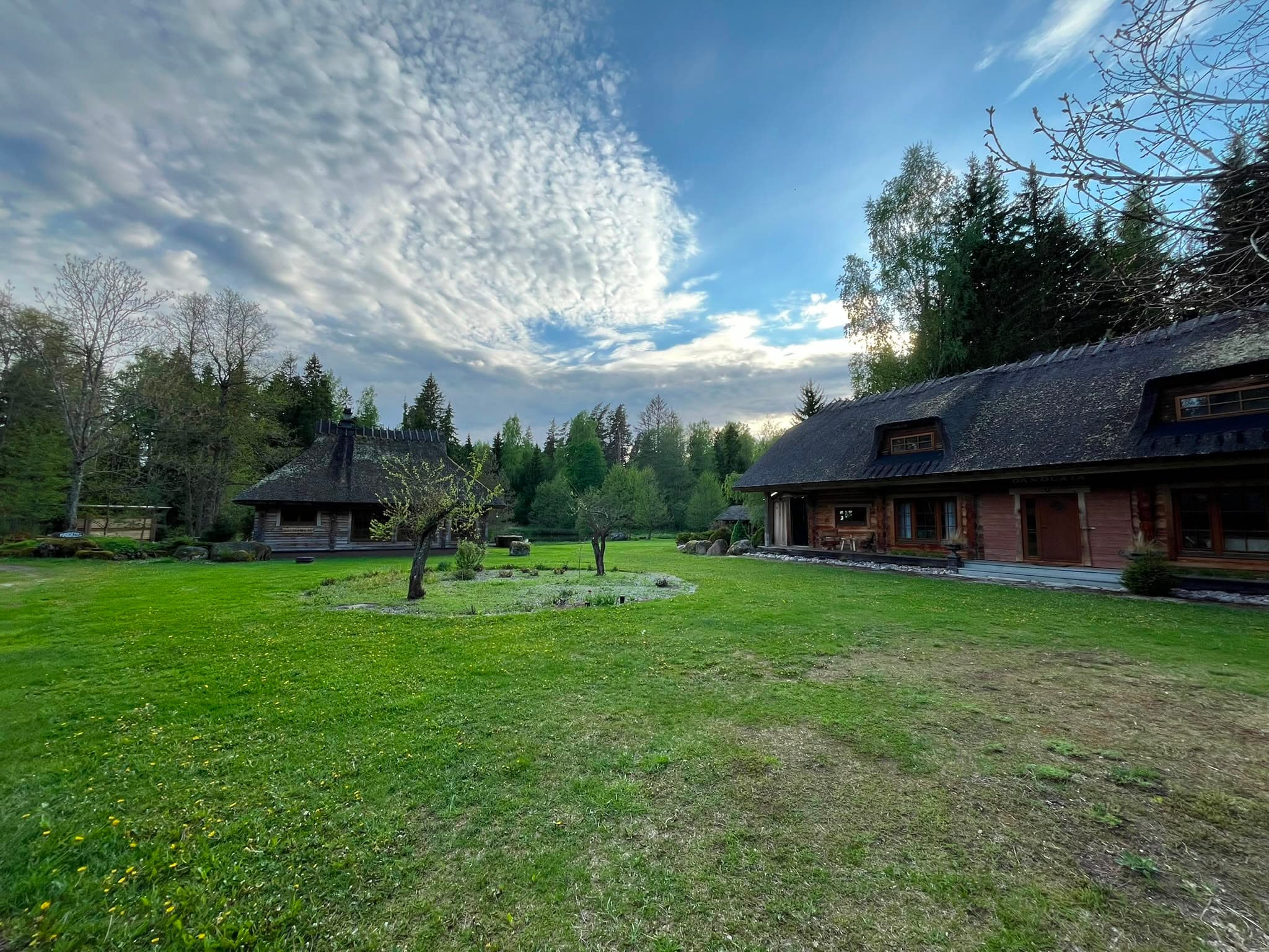 The forecourt lawn between the log buildings