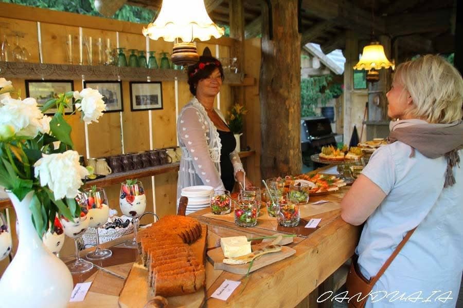 The host behind the laid buffet in the outdoor kitchen, cakes and berry desserts to the front
