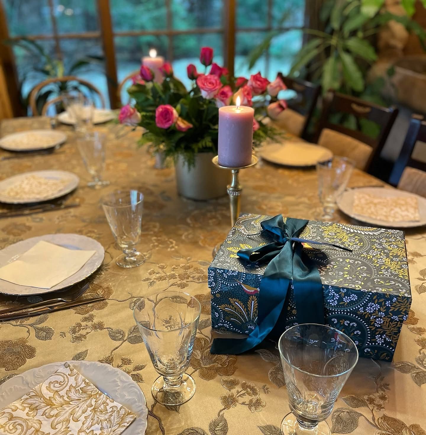 A gold damask cloth with roses, a lit candle and a wrapped gift