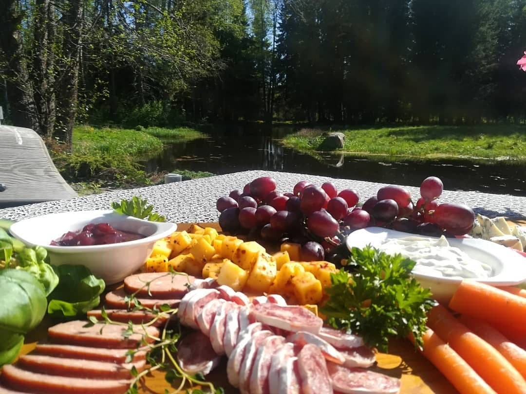 A board of cheese and cured meats by the pond in spring sun