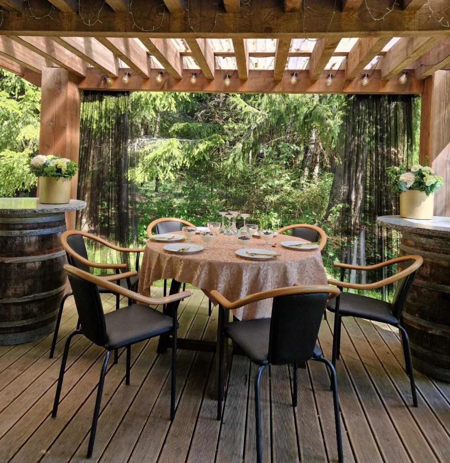 A table laid for six under the pergola, forest behind the curtains