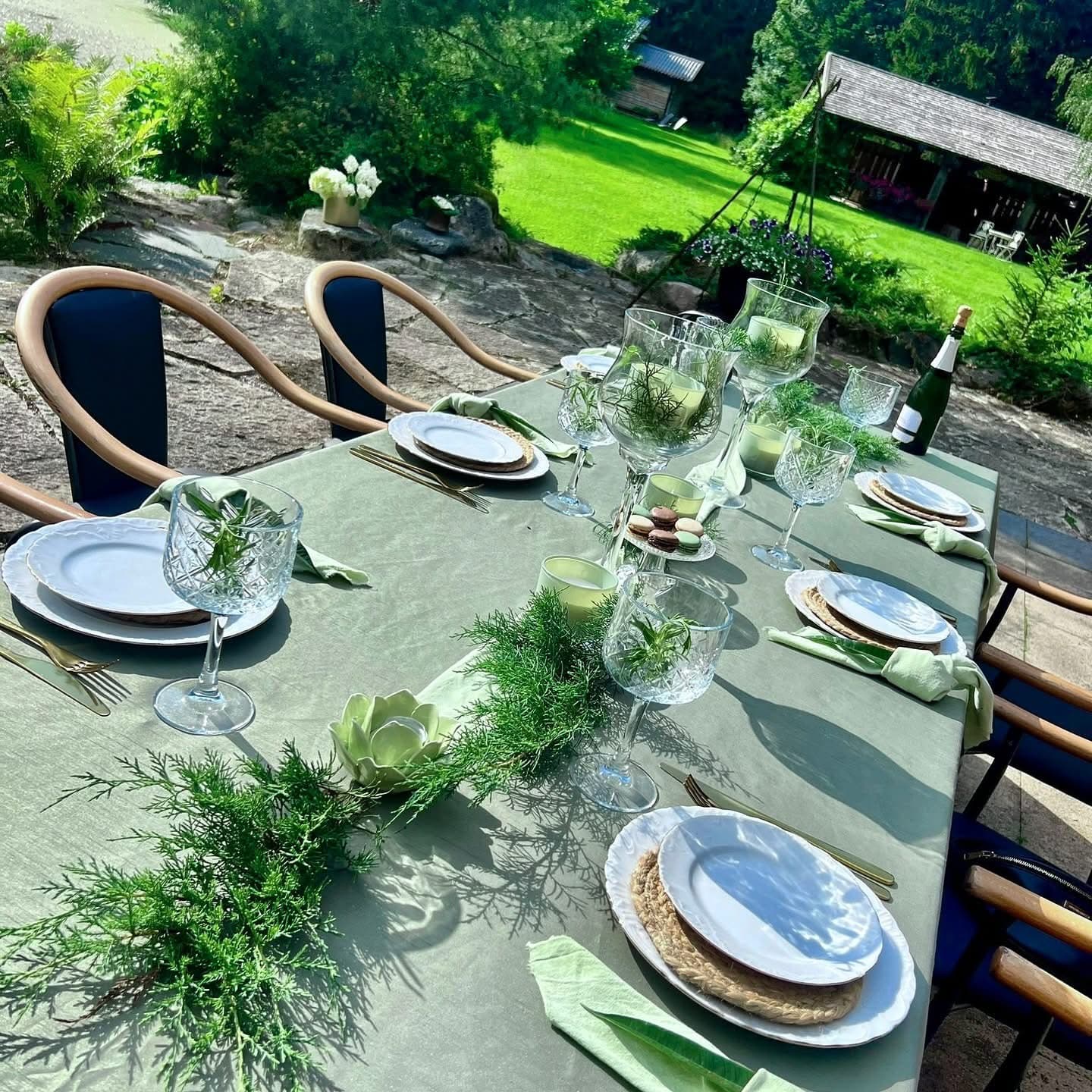 The table laid in green on the stone terrace, crystal and sparkling wine