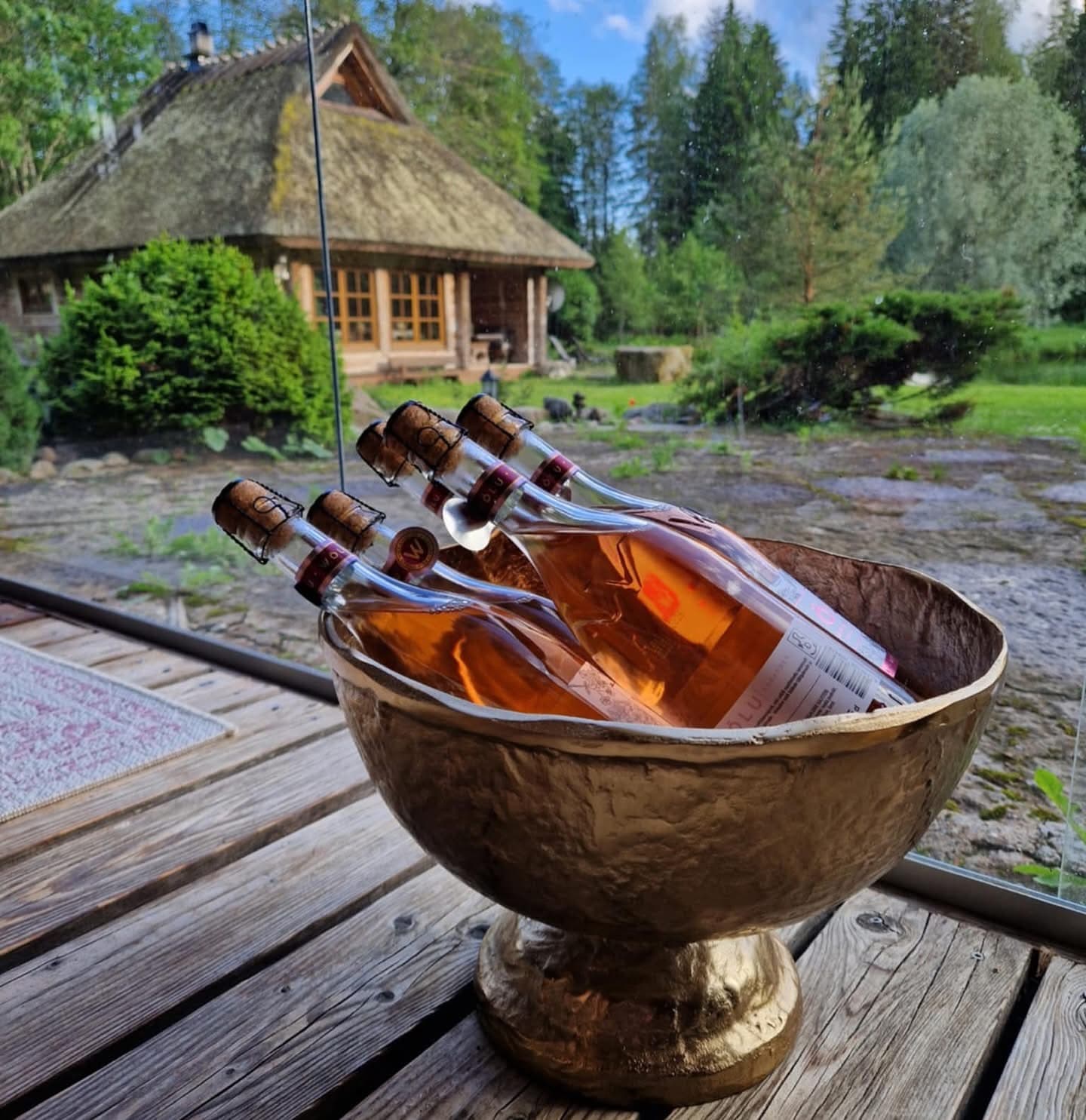 Rosé cooling in a gilded bowl on the deck, the thatched house beyond