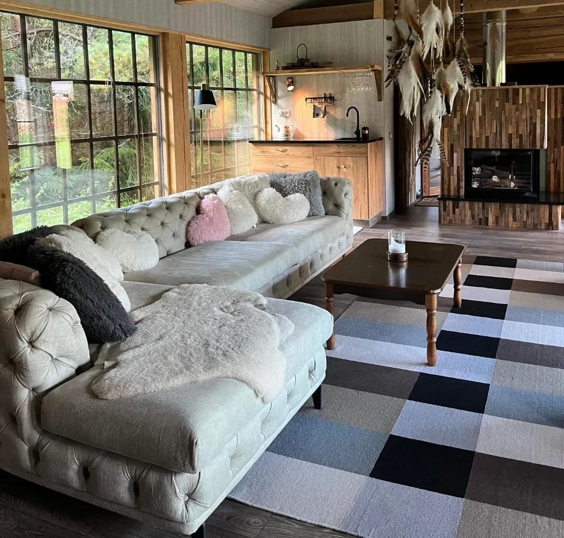 Forest House — the buttoned sofa under sheepskins, a feather dreamcatcher and the kitchen counter behind