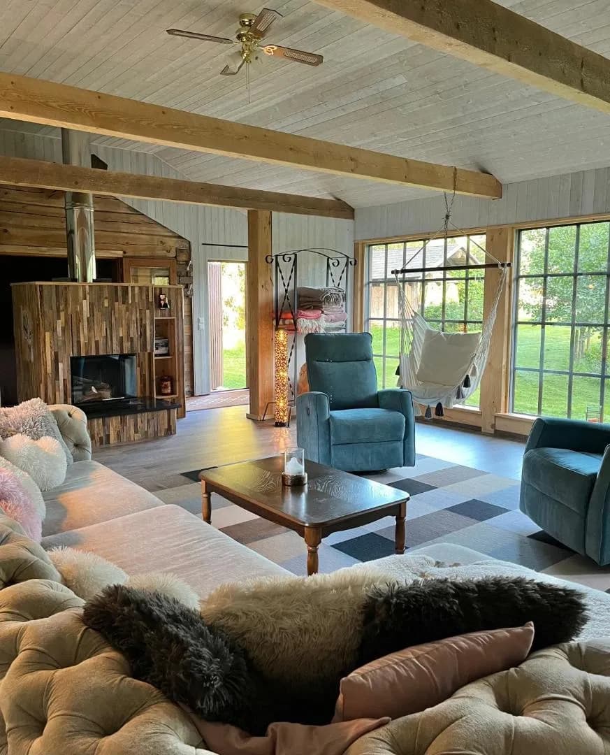 Forest House — the hanging chair at the window, an armchair by the fire and the door onto the lawn