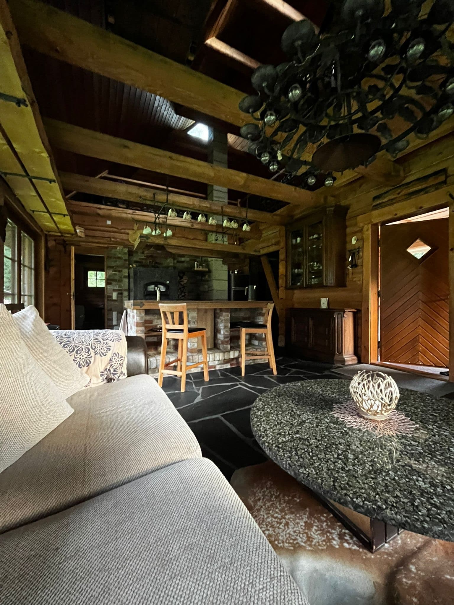 Sauna House — the view from the sofa across the flagstones to the kitchen island, the oak-leaf chandelier overhead