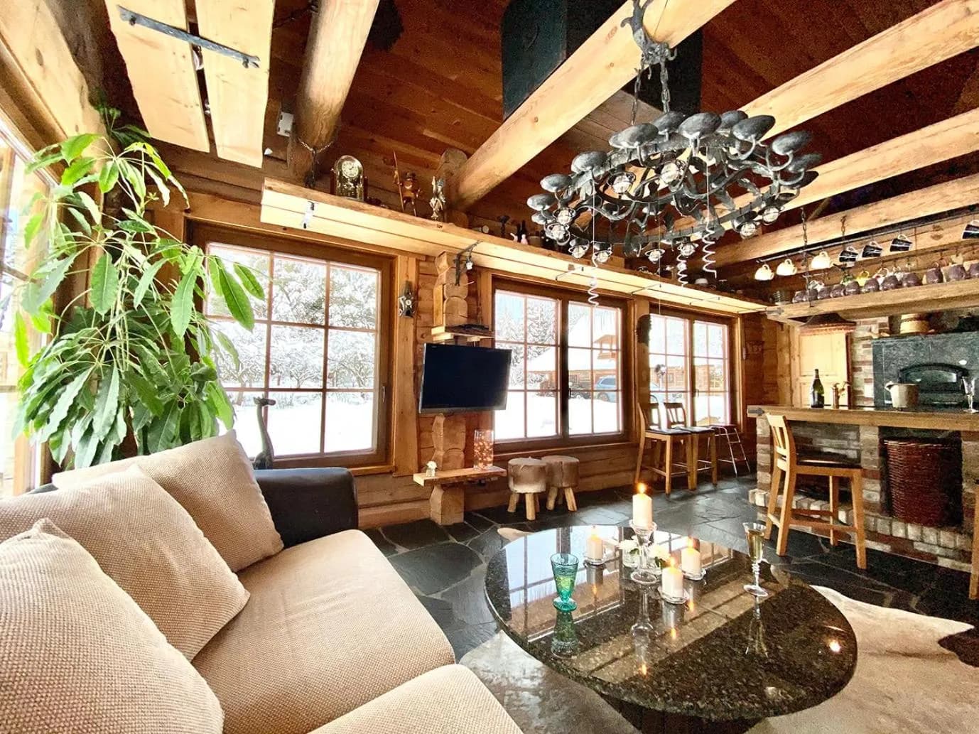 Sauna House — the living room in winter, snow beyond the windows and candles on the granite table