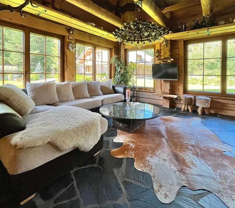 Sauna House — the open living room with sheepskins on the sofa, an oak-leaf chandelier and a flagstone floor