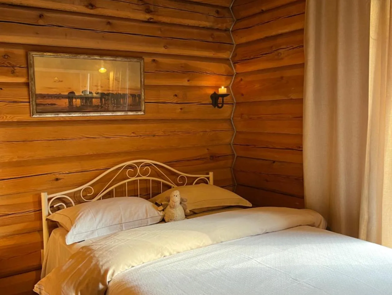 Sauna House — a bed against the log wall, a candle in its sconce and a picture above