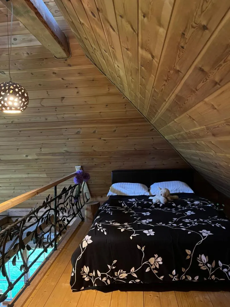 Sauna House — the second bed in the loft, a floral quilt and the forged branch railing