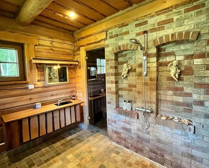 Sauna House — the washroom with its brick shower alcove and the sauna door in the log wall