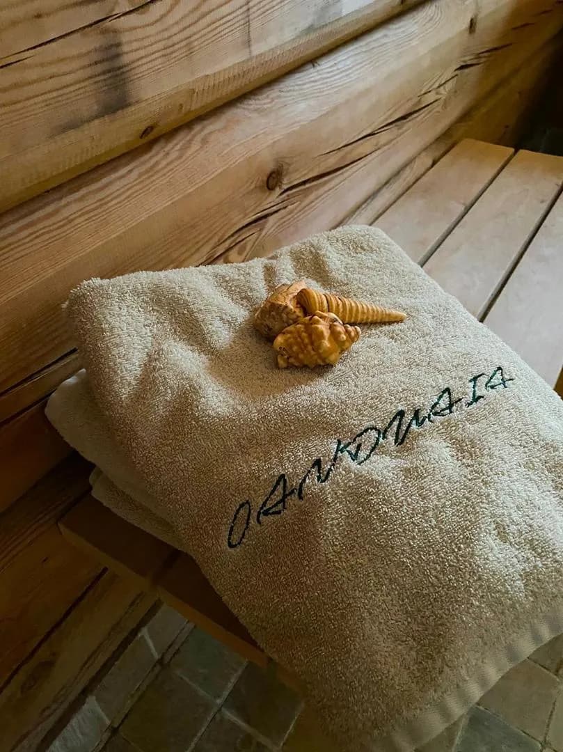 Sauna House — towels embroidered Oanduaia, with shells, on the sauna bench