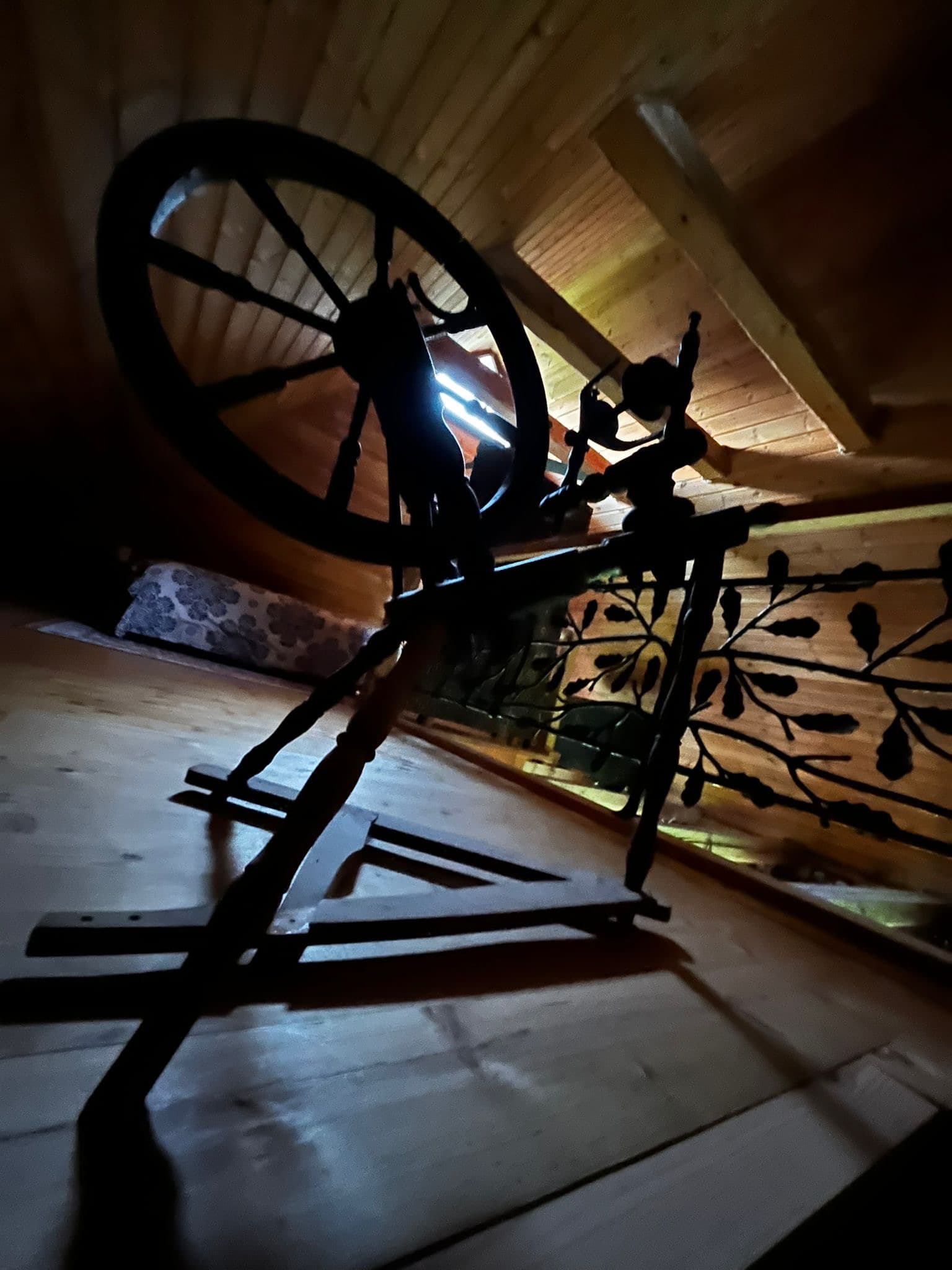 Sauna House — an old spinning wheel on the loft floor beside the forged railing