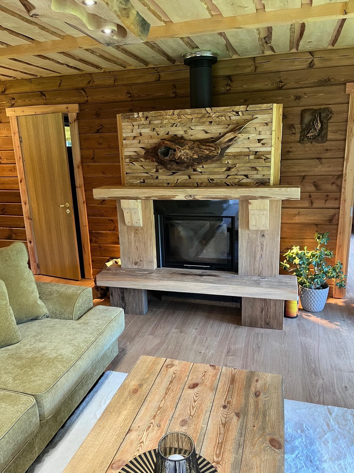 Pond House — the fireplace head-on, a driftwood sculpture set above it and a bench across the hearth