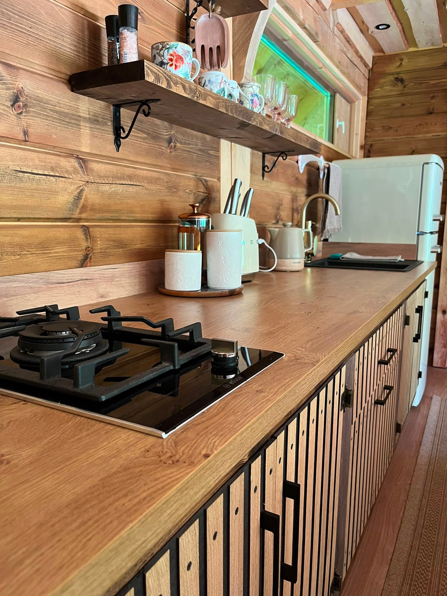 Pond House — the kitchen counter with gas hob, open shelf and retro fridge