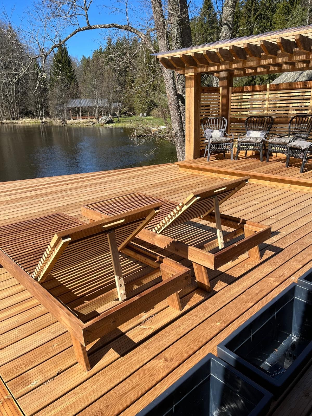 Pond House — the broad timber deck at the pond, loungers and seating under the pergola