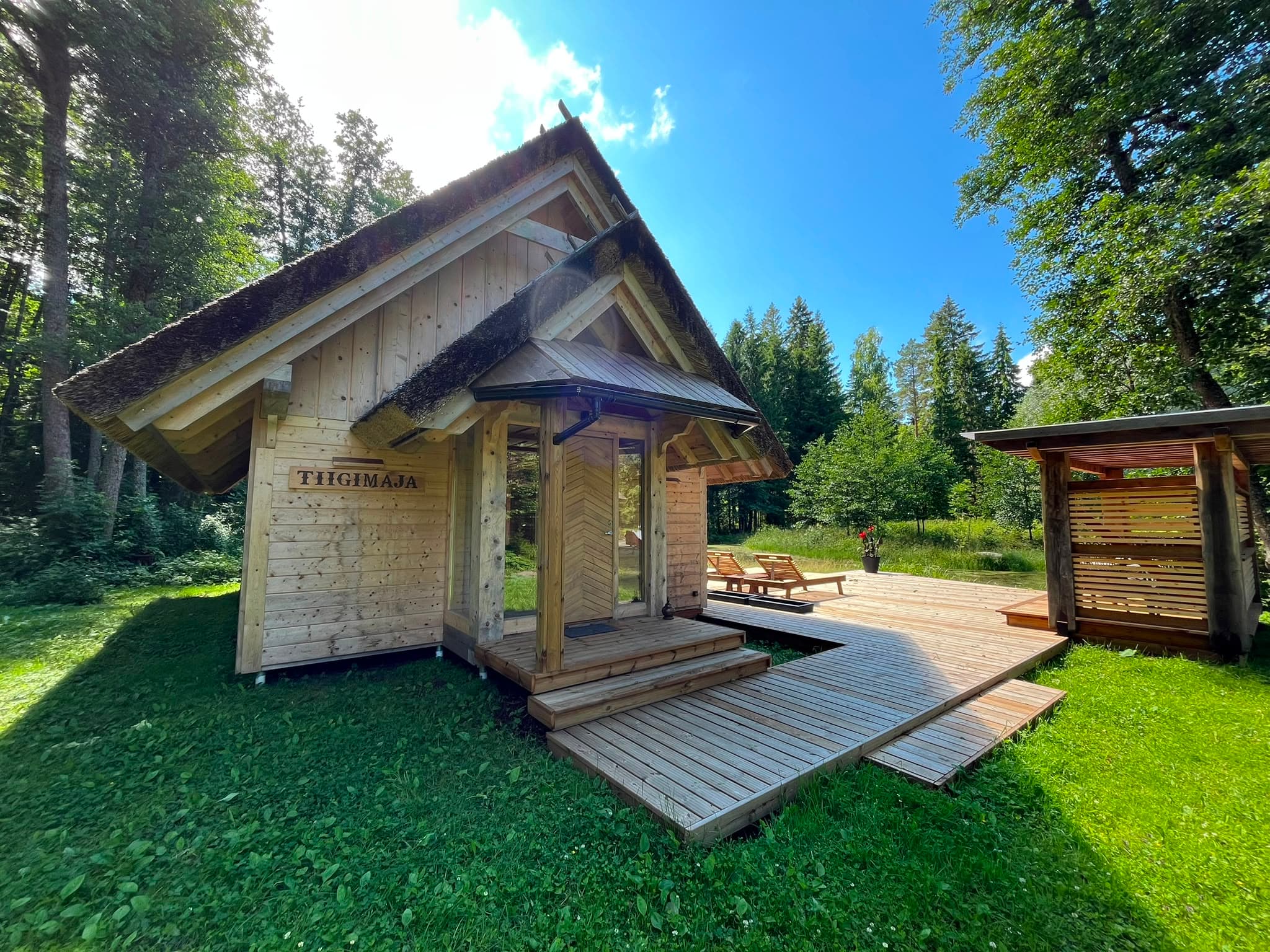 The front of the Pond House, its name carved above the door, deck and loungers