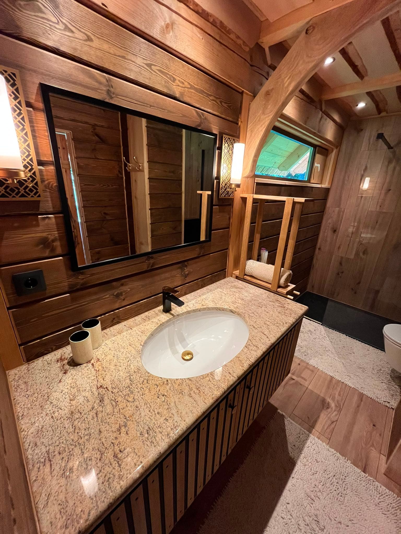 Pond House — the bathroom with a granite vanity and walk-in shower in dark timber