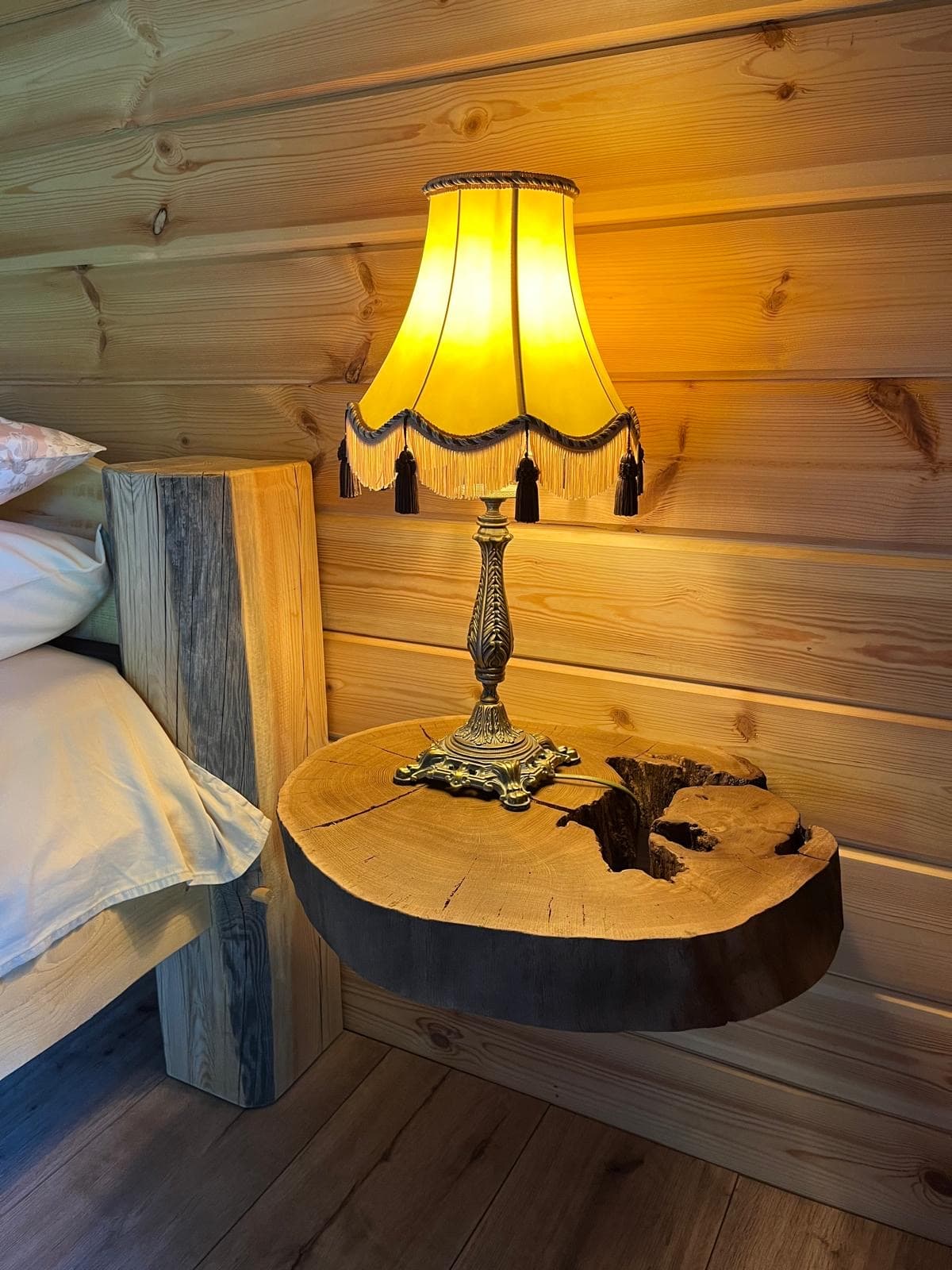 Pond House — a fringed bedside lamp on a shelf cut from a single round of log